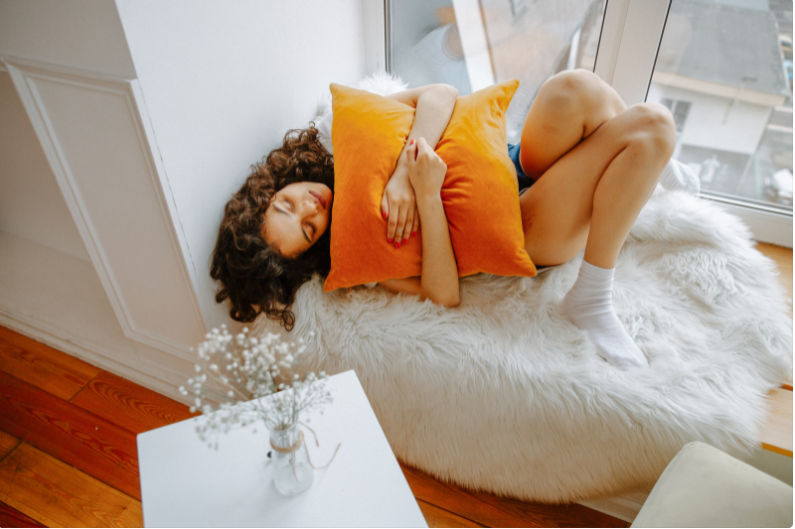 Girl sleeping in a curled position with a orange pillow